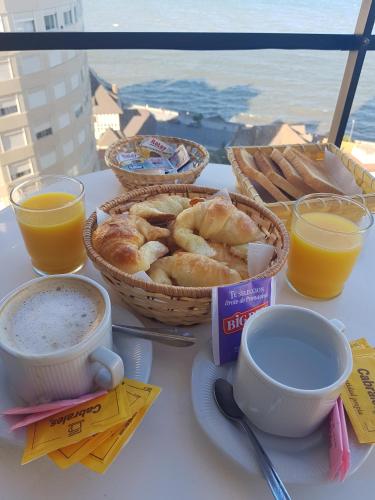 a table with a basket of bread and cups of coffee and orange juice at Club Sol Mar Del Plata in Mar del Plata