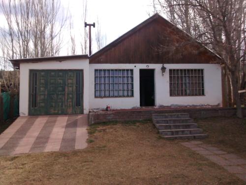 a house with a garage with a green door at Casa de montaña, valle del sol, potrerillos, Mendoza in Mendoza