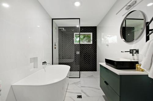 a white bathroom with a tub and a sink at Southern Belle Mollymook in Mollymook