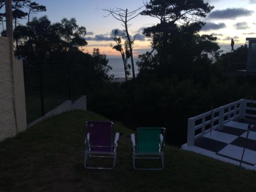 two chairs sitting in the yard with the sunset in the background at Costa Villa in Atlántida
