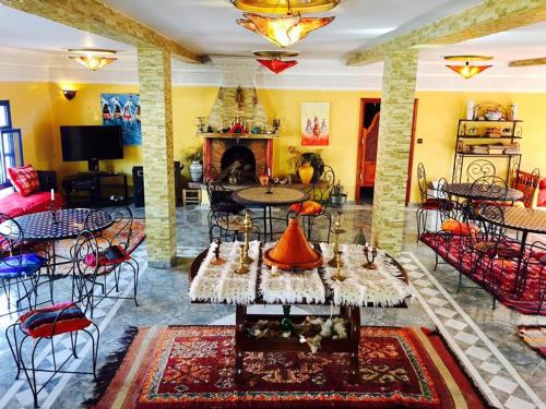 a living room with tables and chairs and a fireplace at Camping & Hôtel Le Calme in Essaouira