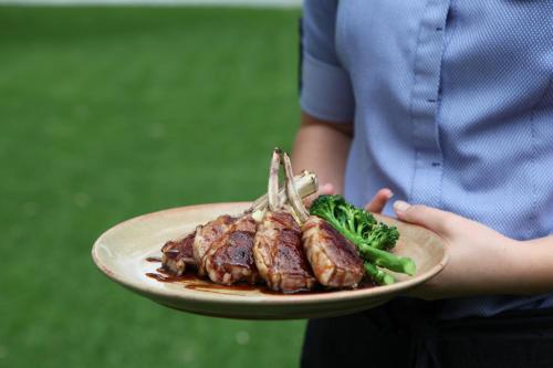 a person holding a plate of meat and broccoli at Pretoria Hotel in Mannum