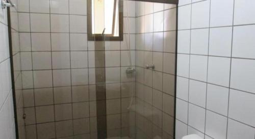 y baño alicatado con ducha y ventana. en Apto Ponta das Canas - Floripa en Florianópolis