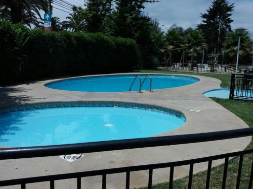 2 piscines dans une cour avec une clôture dans l'établissement Condominio Espacio 1, à La Serena