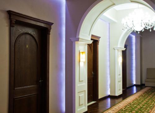an arched hallway with a chandelier and two doors at Sky Luxe Hotel in Astana