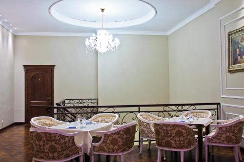 a dining room with tables and chairs and a chandelier at Sky Luxe Hotel in Astana