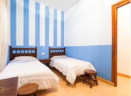 2 camas en una habitación con rayas azules y blancas en Carmen de la Lana en Granada