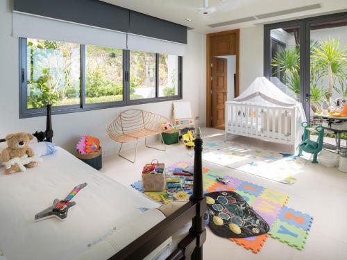 a childs bedroom with a crib and toys on the floor at Malaiwana Villas in Nai Thon Beach