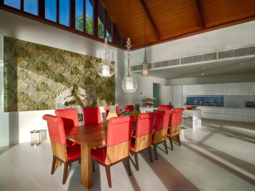 a dining room with a wooden table and red chairs at Malaiwana Villas in Nai Thon Beach