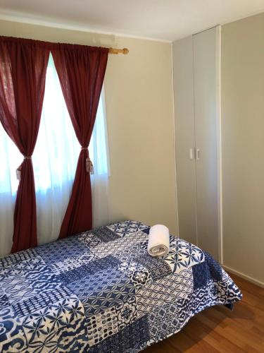 a bedroom with a bed with a blue and white blanket at Cabañas Los Laureles - Lican Ray in Licán Ray