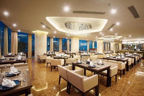 a restaurant with tables and chairs and a chandelier at Avatar Danang Hotel in Da Nang