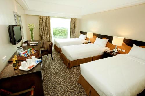 a hotel room with two beds and a television at Hotel Elizabeth Cebu in Cebu City