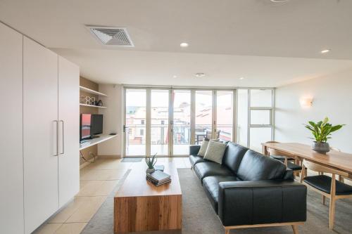 a living room with a black couch and a table at Sullivans Cove Apartments in Hobart
