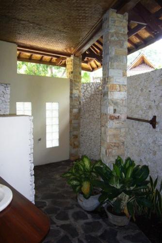 a room with potted plants and a stone wall at Jukung Bali Bungalow in Amed