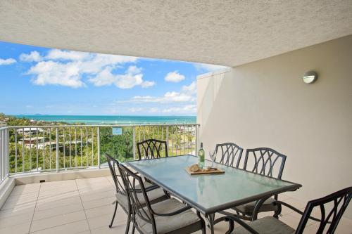 a dining room with a table and chairs on a balcony at Azure Sea Whitsunday Resort in Airlie Beach