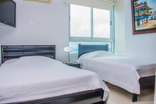 1 dormitorio con 2 camas y ventana en De Lujo-Palmetto Eliptic Playa Panoramico, en Cartagena de Indias