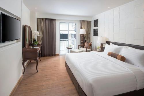 a hotel room with a large white bed and a desk at Casa Vimaya Riverside in Bangkok