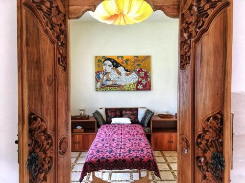 a bedroom with a wooden door with a bed at Sun Suko Boutique Resort in Pemuteran