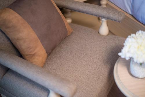 a chair with a vase of flowers next to a table at Casa Vimaya Riverside in Bangkok