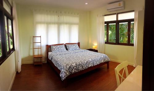 a bedroom with a bed and two windows at Baan2rai in Kanchanaburi