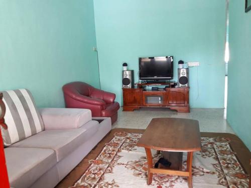 a living room with a couch and a tv at Homestay Ustaz in Taiping