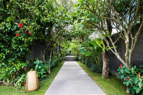 a walkway in a garden with trees and flowers at The One Boutique Villa & Spa Seminyak in Seminyak
