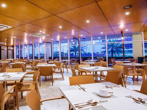a dining room with tables and chairs and windows at Hotel101 - Manila in Manila
