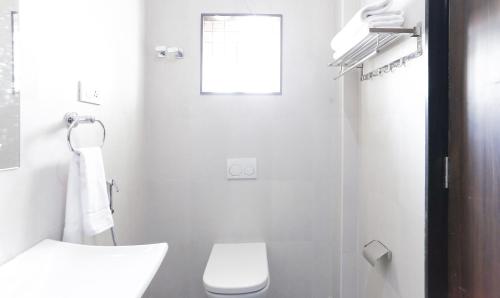 a white bathroom with a toilet and a shower at Treebo Hi Line Apartments Kalapatti in Coimbatore