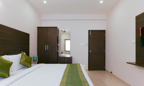 a bedroom with a large white bed with green pillows at Treebo Hi Line Apartments Kalapatti in Coimbatore