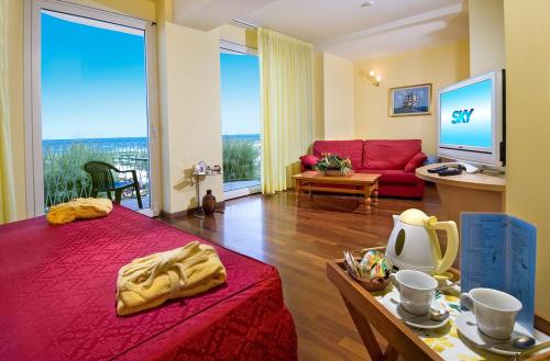 a bedroom with a red bed and a living room at Hotel Resort Marinella in Gabicce Mare