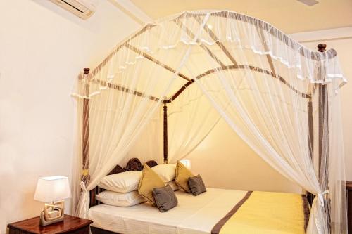 a bedroom with a canopy bed with white drapes at Horizon Villa in Unawatuna