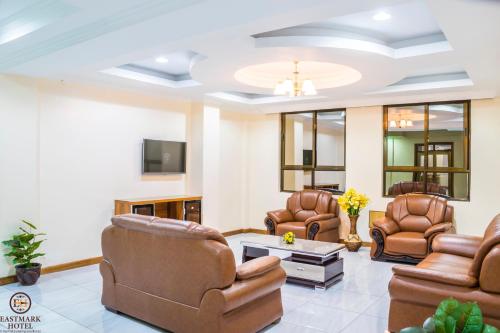 a living room with leather chairs and a tv at Eastmark Hotel in Nakuru