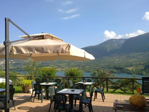 un patio con tavoli, sedie e ombrellone di La Poiana a Barrea