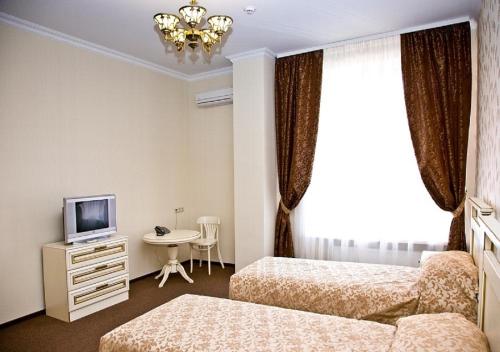 ein Hotelzimmer mit 2 Betten und einem TV in der Unterkunft Hotel Elbuzd in Rostow am Don