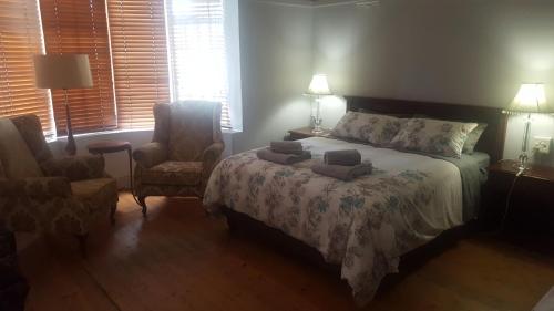 a bedroom with a bed and a chair and a window at Pretoria Inn in Pretoria