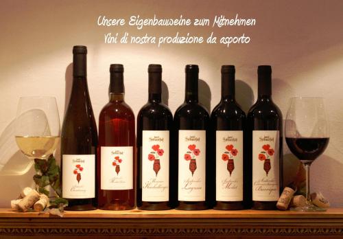 a group of wine bottles on a shelf with wine glasses at Hotel Sittnerhof in Merano