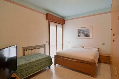 a bedroom with a bed and a flat screen tv at Strand Lungomare Apartment in Cesenatico