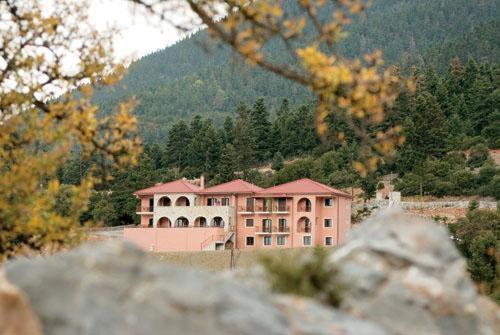 duży różowy budynek przed górą w obiekcie Vytina Mountain View Hotel w mieście Vytina