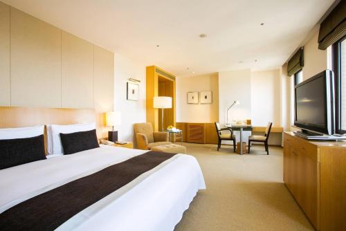 a hotel room with a bed and a flat screen tv at Ambassador Hotel Hsinchu in Hsinchu City