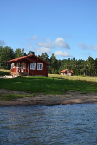 una casa roja en la orilla de un cuerpo de agua en Holiday Cottage Tiira, en Raseborg