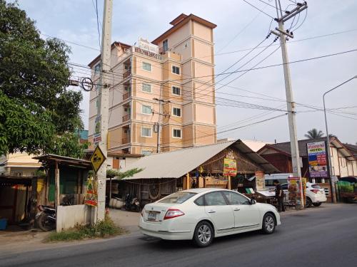 biały samochód zaparkowany przed wysokim budynkiem w obiekcie Baanpak Sam Anong w mieście Hua Hin