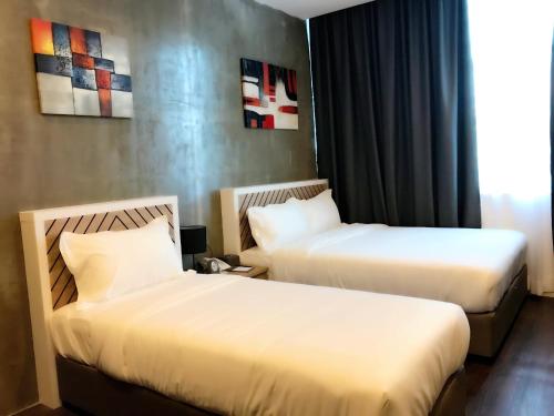 a hotel room with two beds and a window at K Boutique Hotel in Teluk Intan