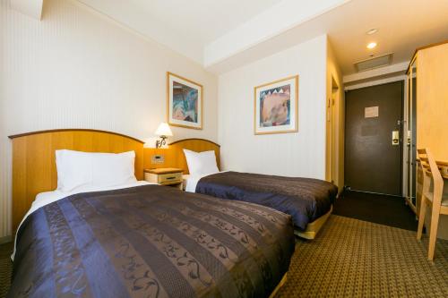 a hotel room with two beds and a table at Hotel Resol Sapporo Nakajima Koen in Sapporo