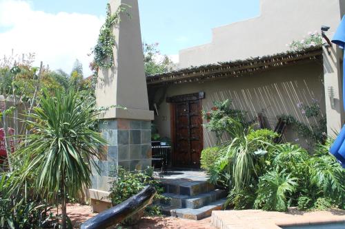 a house with a wooden door and some plants at African Roots Guest House in Polokwane