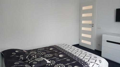 a bedroom with a black and white bed and a dresser at Apartament Centrum 1 in Mikołajki
