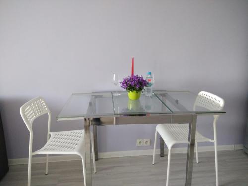 ワルシャワにあるApartment Plac Bankowyのガラステーブル(椅子2脚付)と紫の花瓶