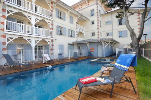 - une piscine avec des chaises à côté d'un bâtiment dans l'établissement Résidence Néméa Le Marché de la Plage, à Mimizan-Plage