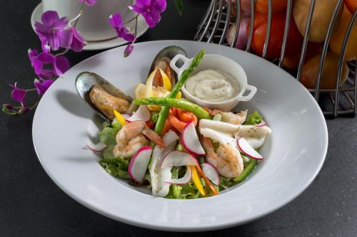 a white plate with a salad with shrimp and vegetables at BYD Lofts - Boutique Hotel & Serviced Apartments - Patong Beach, Phuket in Patong Beach