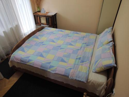 a bed with a colorful quilt on it in a room at Smeštaj - sobe MARVEL in Niš