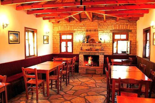 a restaurant with tables and chairs and a fireplace at Aloni Guesthouse in Ano Pedina